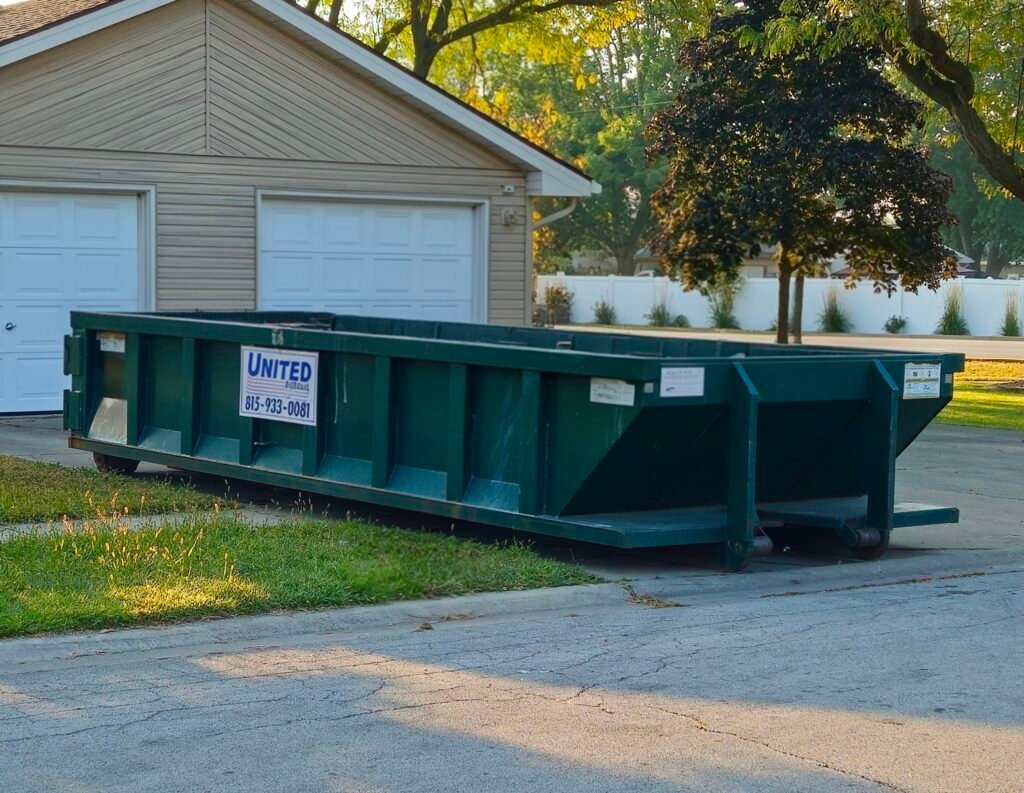 Green dumpster rental on a residential street. Waste container for home renovation, cleanout, or construction debris.