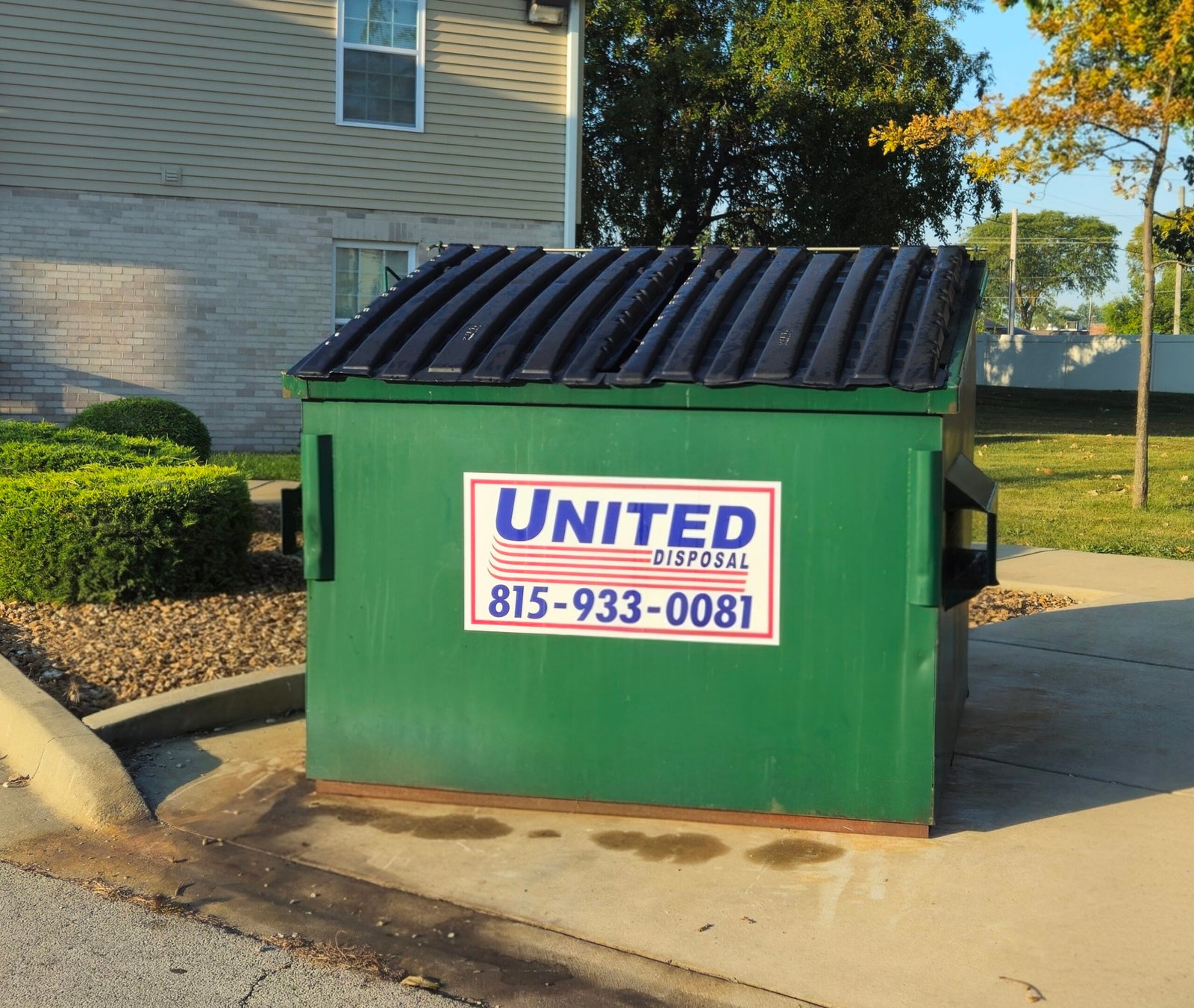Green United Disposal dumpster with black lid. Waste management services.