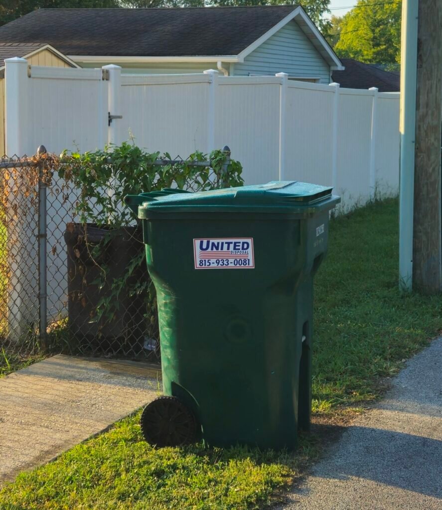 Green United Disposal trash can on a home's lawn. Waste management services.