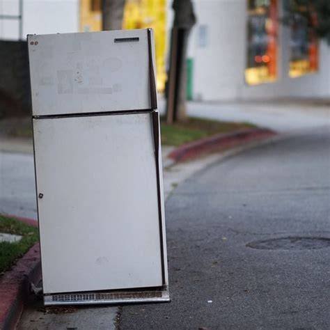 Discarded refrigerator on street. Illegal dumping, difficult waste management. Environmental pollution.