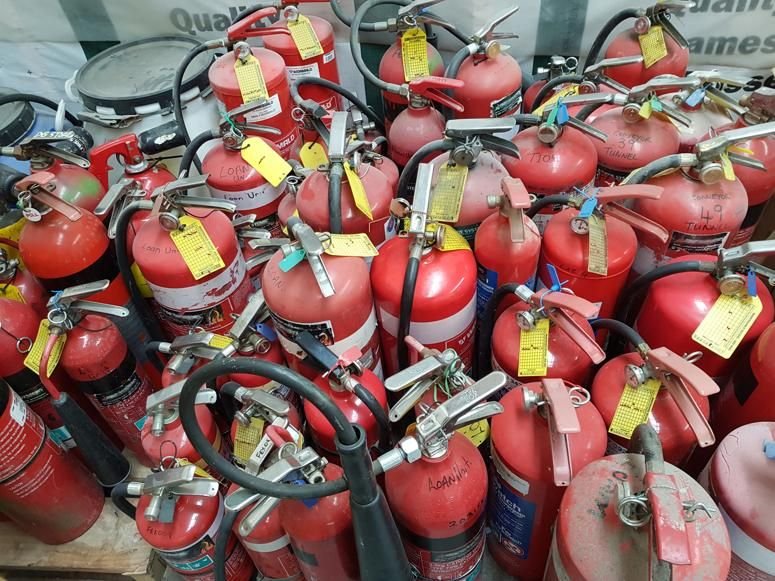 Pile of used, red fire extinguishers. Difficult waste disposal.