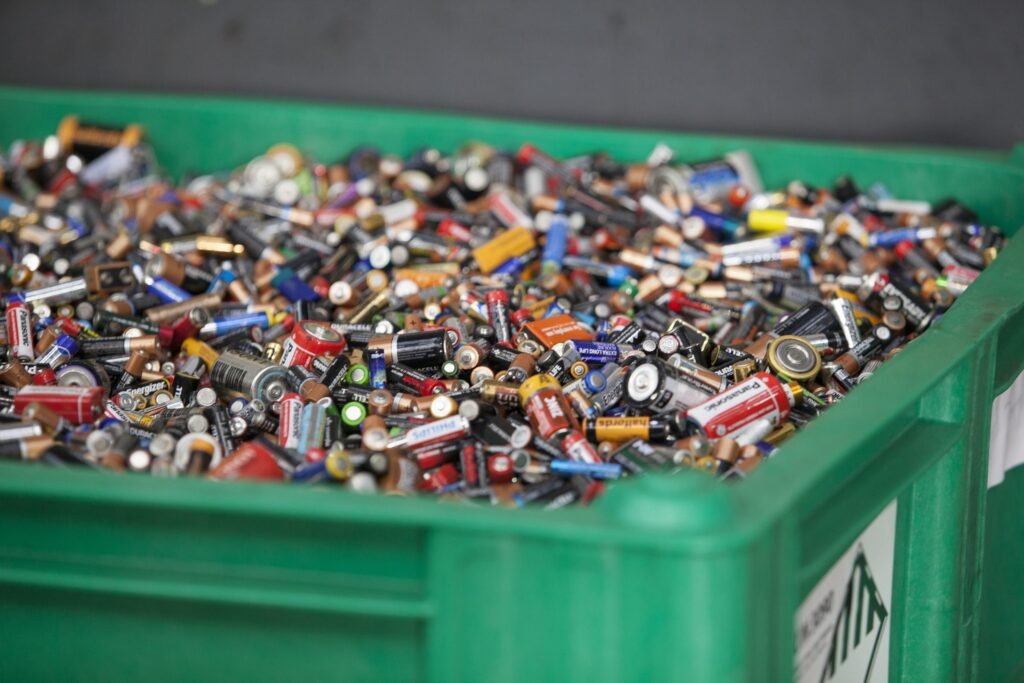 Difficult waste: Used batteries in a green recycling container. Battery recycling.