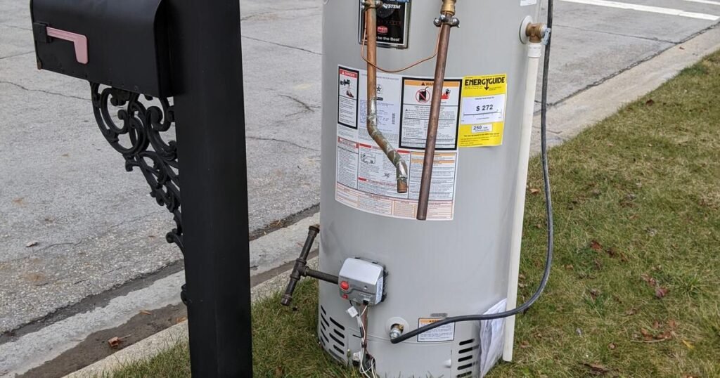 Difficult waste: Discarded water heater next to mailbox. Appliance disposal problem.
