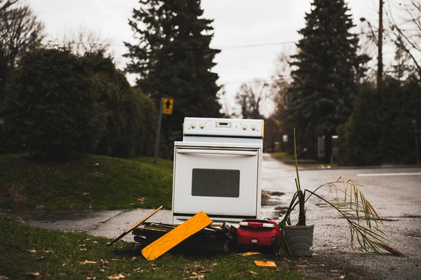 Difficult waste: Discarded stove and other items on the curb. Illegal dumping, environmental pollution.