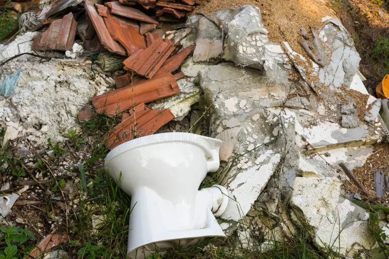 Difficult Waste: Toilet bowl amidst construction waste. Close-up shot, natural light.